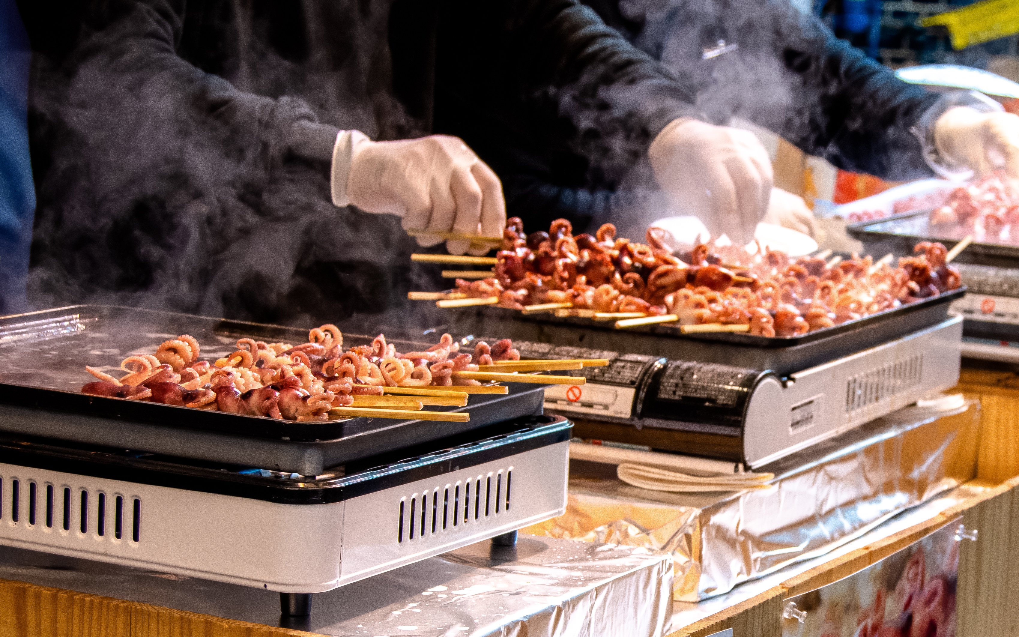 Grilled octopus skewers cooking at Tsukiji Fish Market in Tokyo.