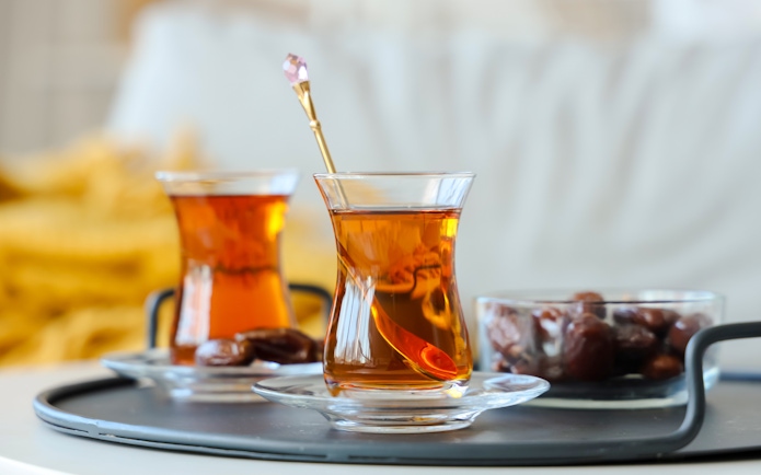 Turkish tea in glass cups with dates on a tray.