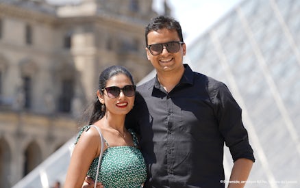 Couple posing in front of the Louvre Pyramid during a professional photoshoot in Paris.