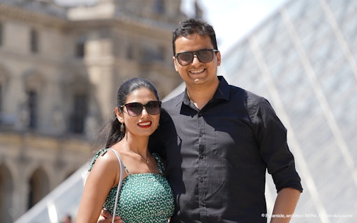 Couple posing in front of the Louvre Pyramid during a professional photoshoot in Paris.
