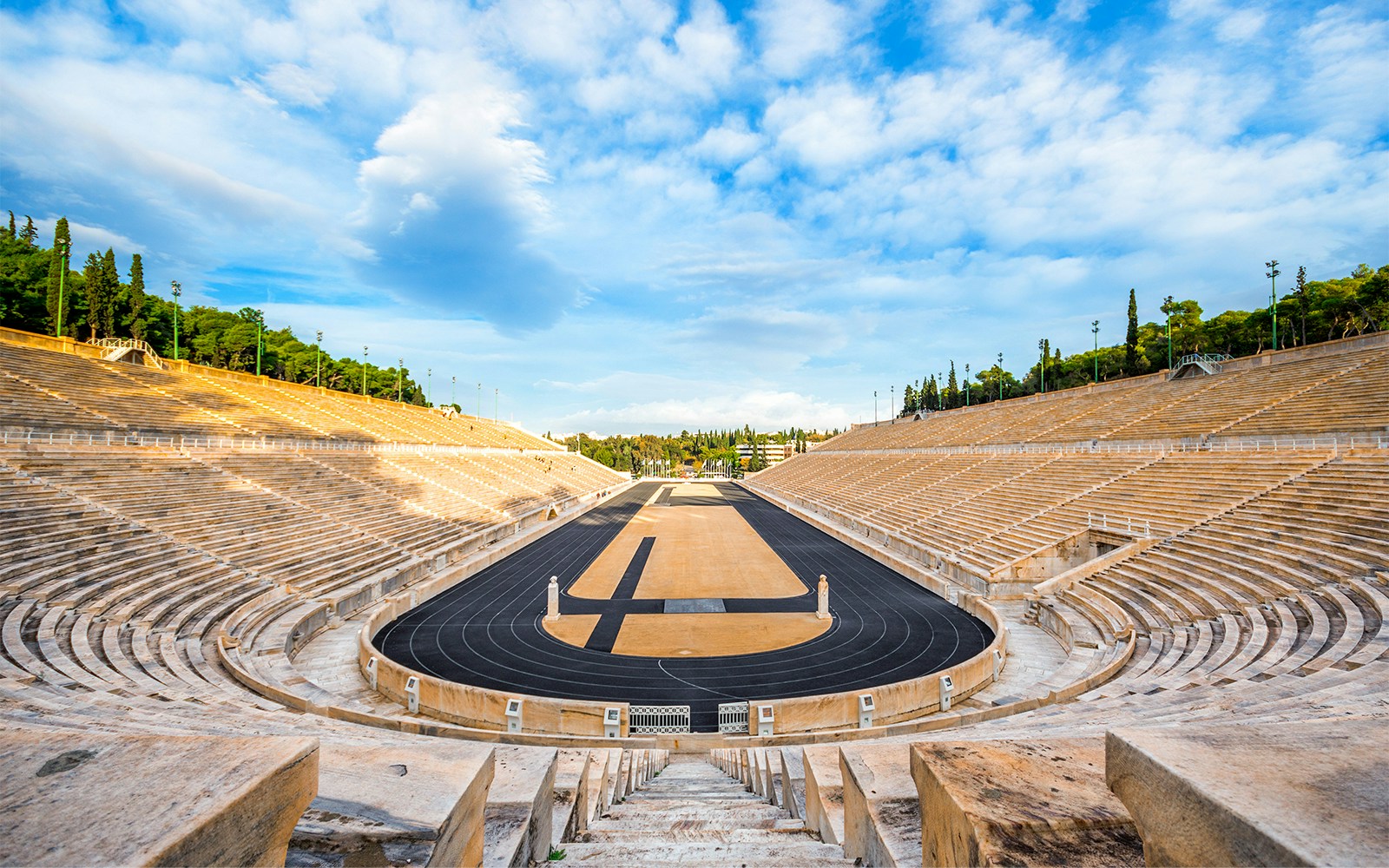 Ancient Olympic Stadium in Athens with hop on hop off tour bus in foreground.