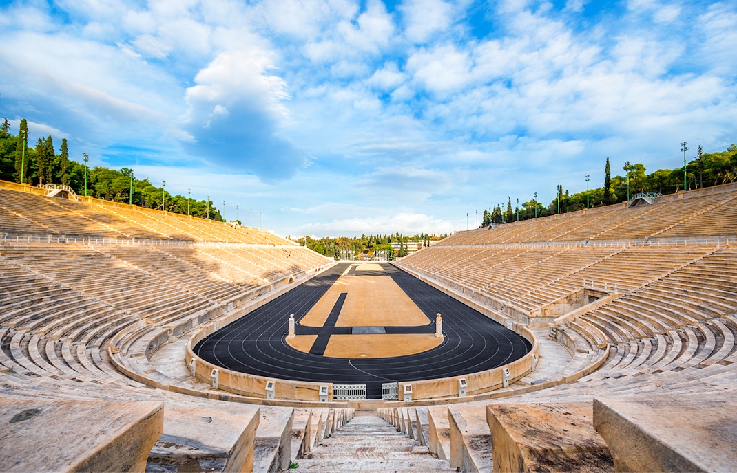 Ancient Olympic Stadium in Athens with hop on hop off tour bus in foreground.