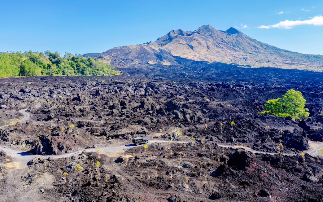 Off-road vehicle on black lava field near Mount Batur, Bali.