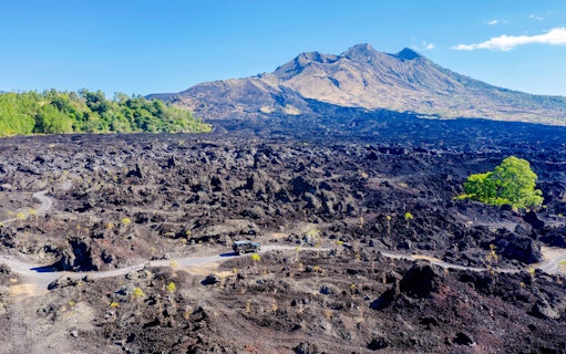 Off-road vehicle on black lava field near Mount Batur, Bali.