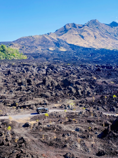 Off-road vehicle on black lava field near Mount Batur, Bali.