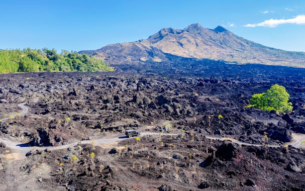 Off-road vehicle on black lava field near Mount Batur, Bali.