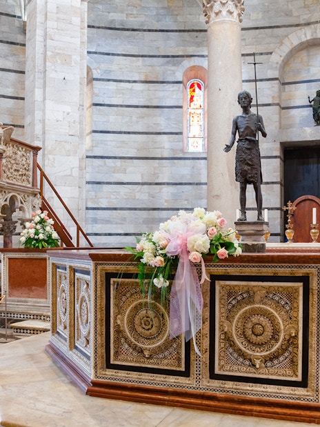 Baptistery of Pisa interior with ornate pulpit and floral decorations.