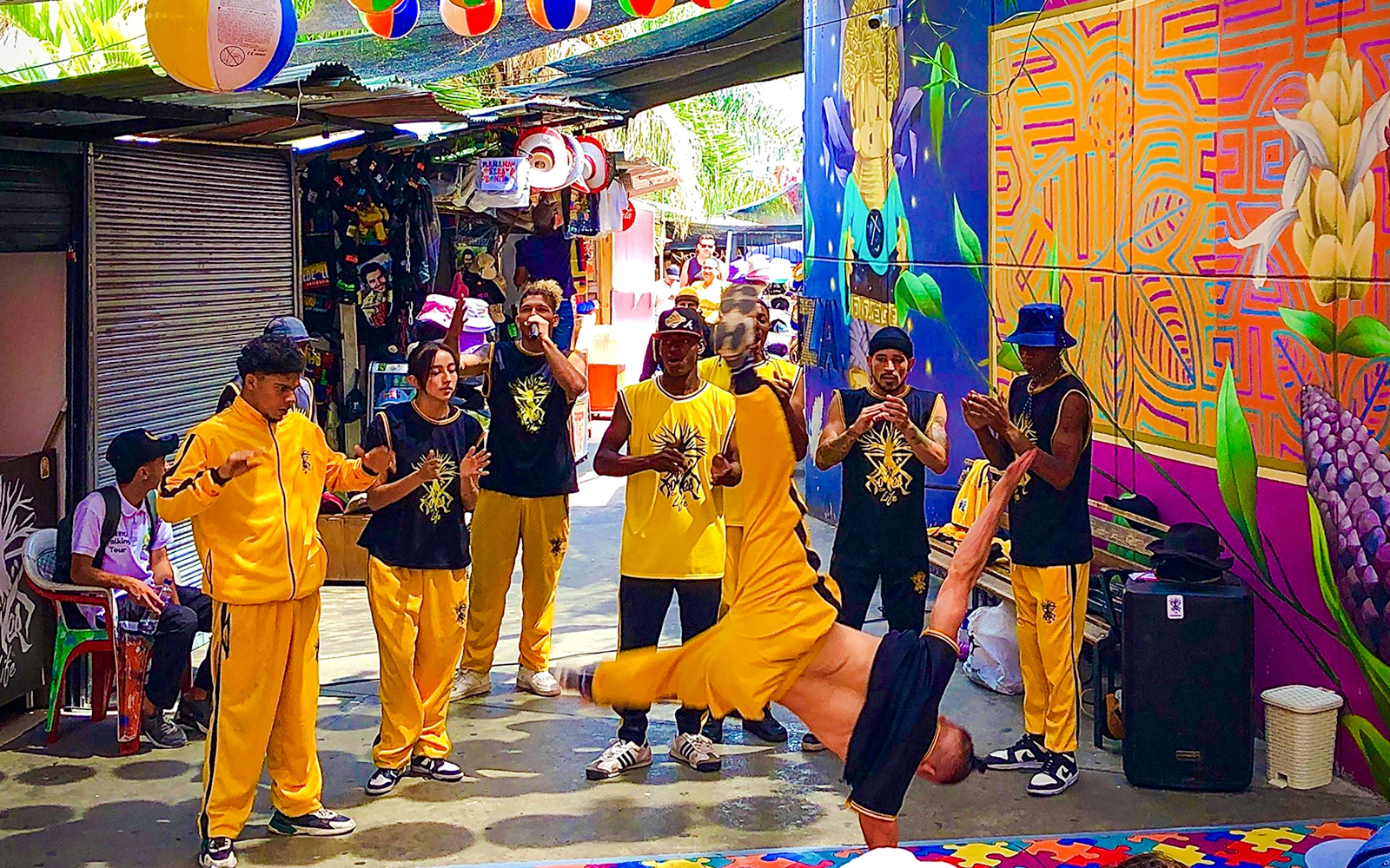Guests watching a street dance performance in Medellin's Comuna with vibrant graffiti murals.