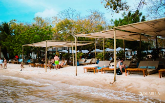 Beachfront lounge area with sunbeds and shade structures on Rosario Islands, Cartagena.