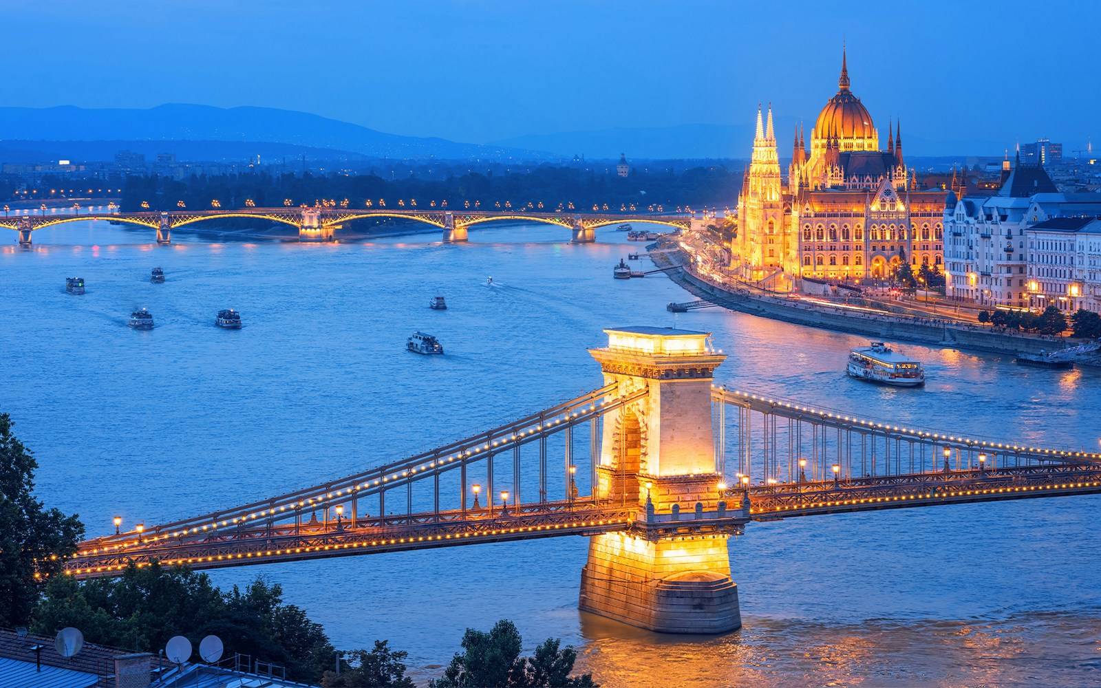 Budapest skyline with illuminated Parliament building along Danube River at dusk, Hungary.