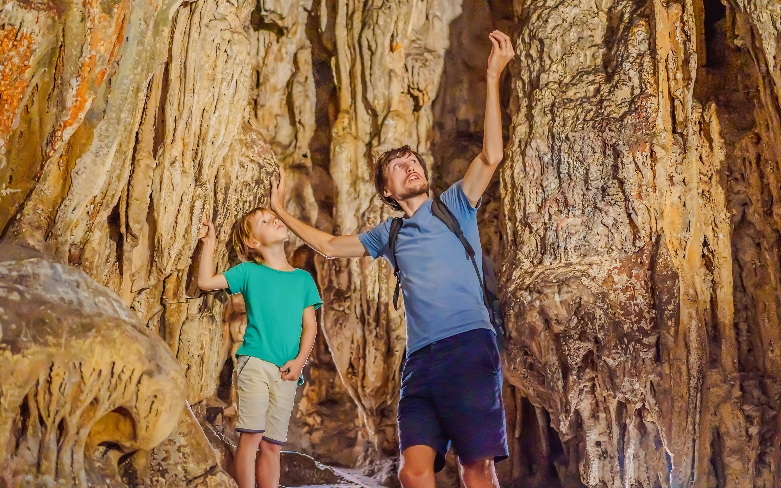 Family exploring stalactites in Sung Sot Cave, Ha Long Bay, Vietnam.