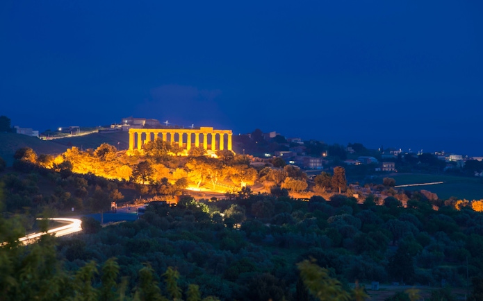 Light trail leading to illuminated Temple Valley, Agrigento at night.