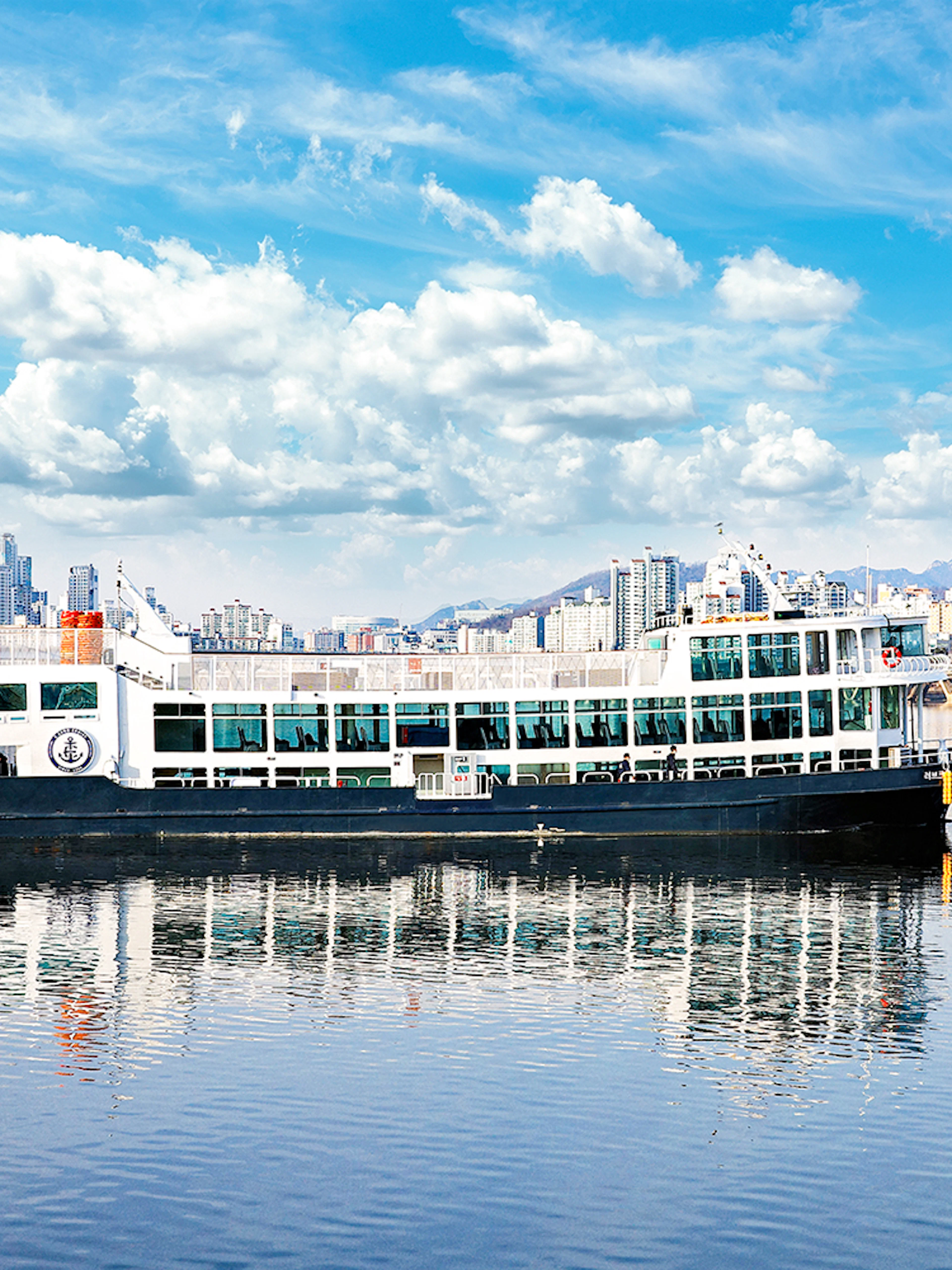 Eland Cruise ship on Hangang River with Seoul skyline in the background.