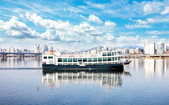 Eland Cruise ship on Hangang River with Seoul skyline in the background.