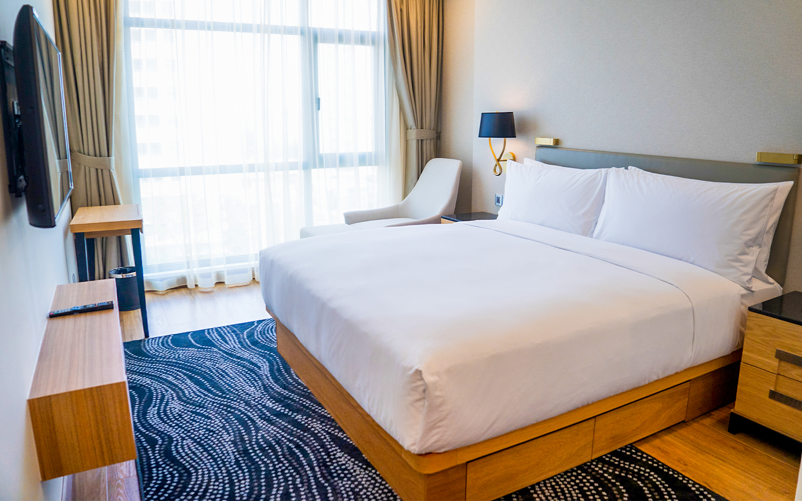 Budget-friendly hotel room with double bed, modern decor, and large window.