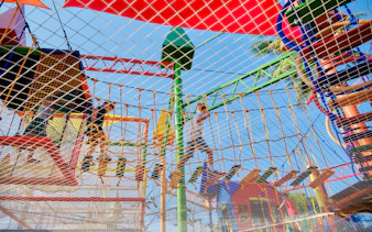 Children navigating a colorful rope course at a birthday party in Phuket.