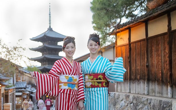 Two people in kimonos at Kiyomizu Temple, Kyoto, with a pagoda in the background.
