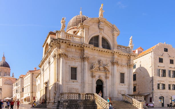 Dubrovnik Old Town, St. Blaise Church facade with tourists exploring.