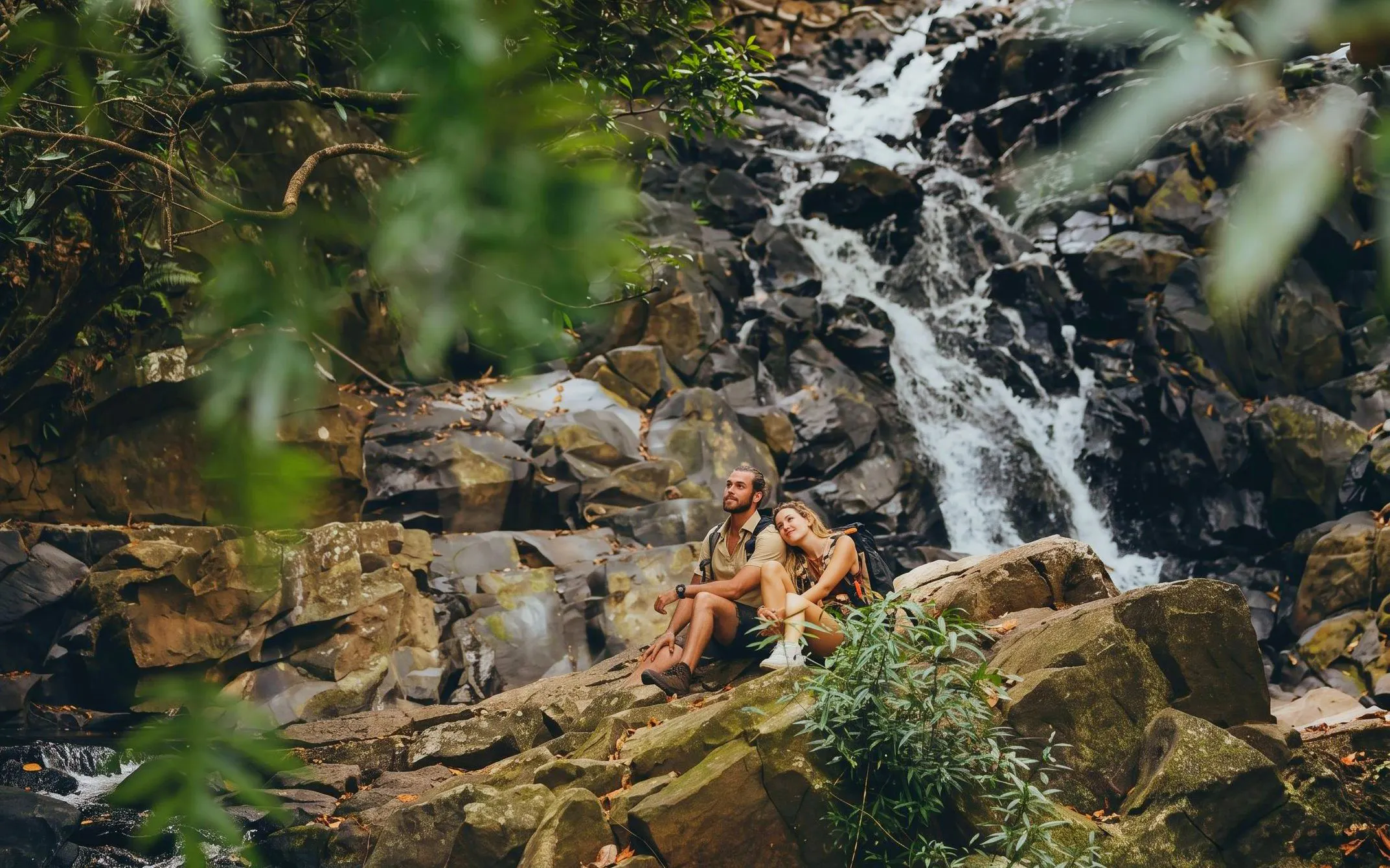 Couple sitting by a waterfall in Bel Ombre wilderness tour.