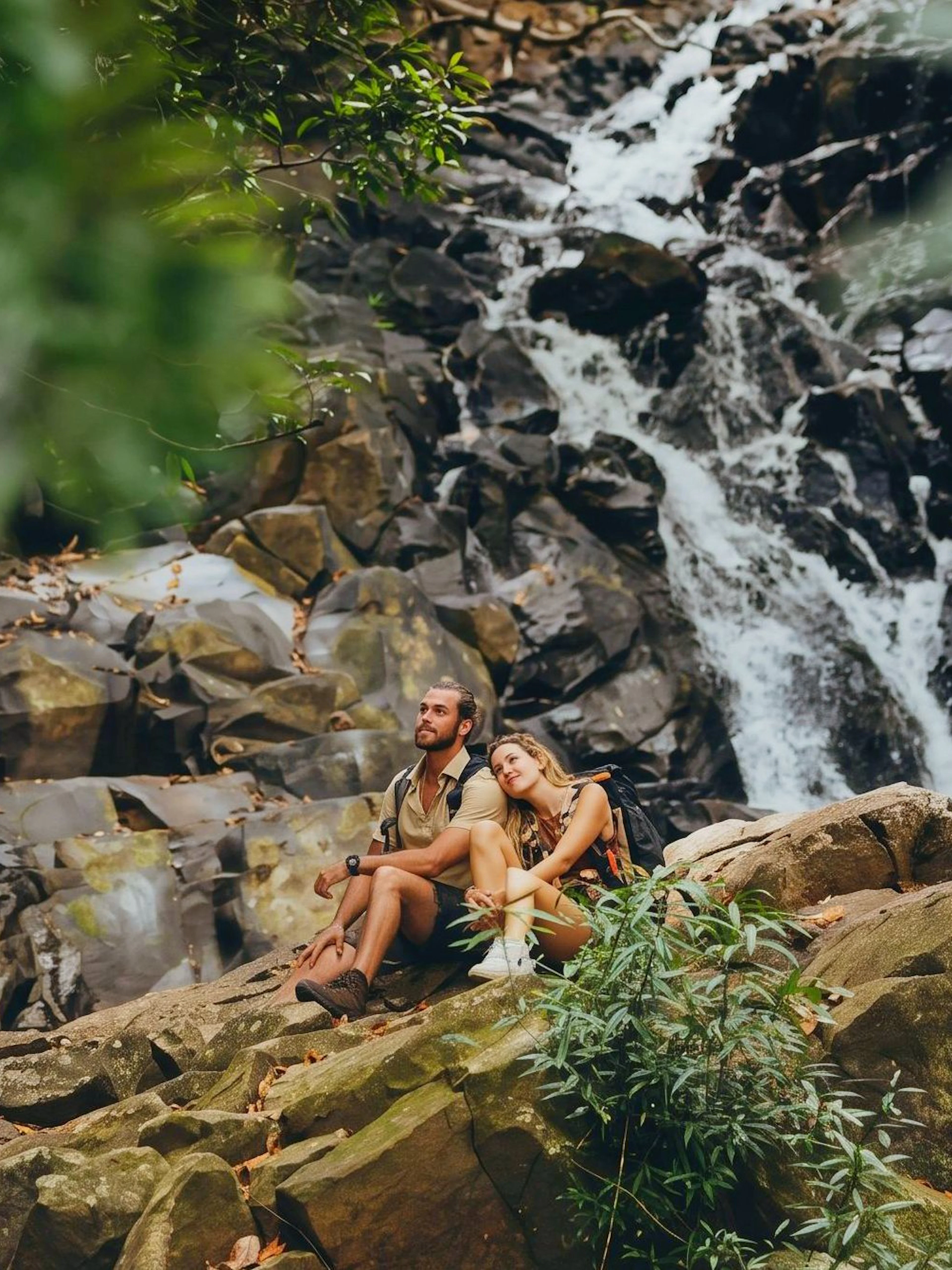 Couple sitting by a waterfall in Bel Ombre wilderness tour.