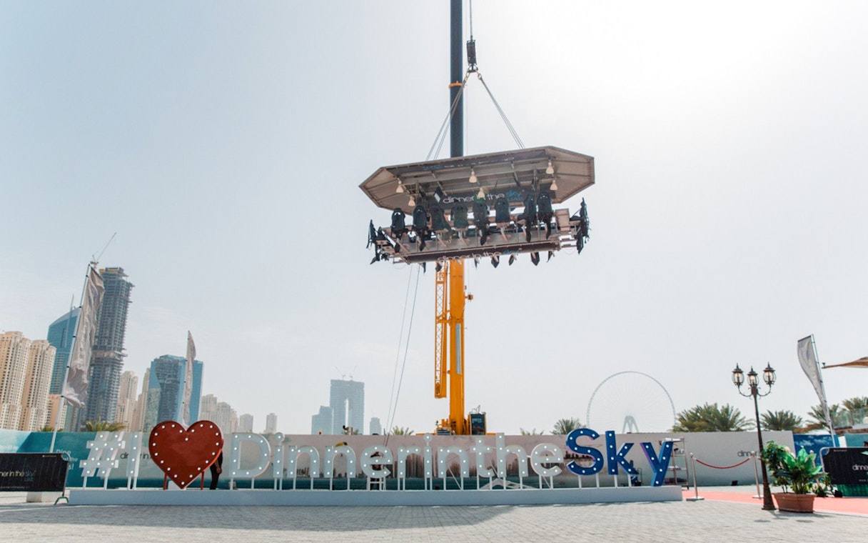 Dinner in the Sky experience suspended above Dubai with city skyline in background.