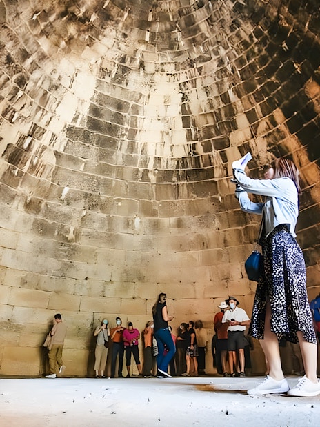 Tourists exploring the interior of the round tomb of Agamemnon in Mycenae.