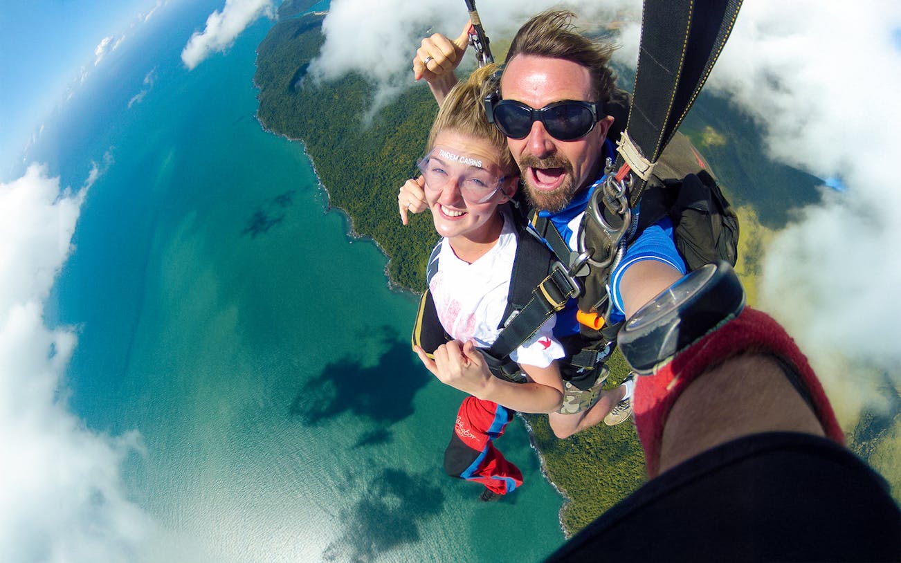 Tandem skydive over Cairns coastline with ocean and forest views.