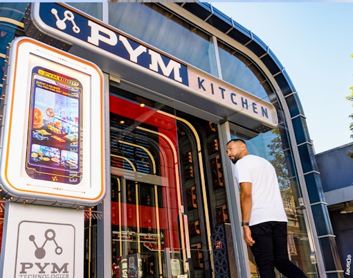 Entrance of PYM Kitchen at Disneyland Paris with a digital menu display.
