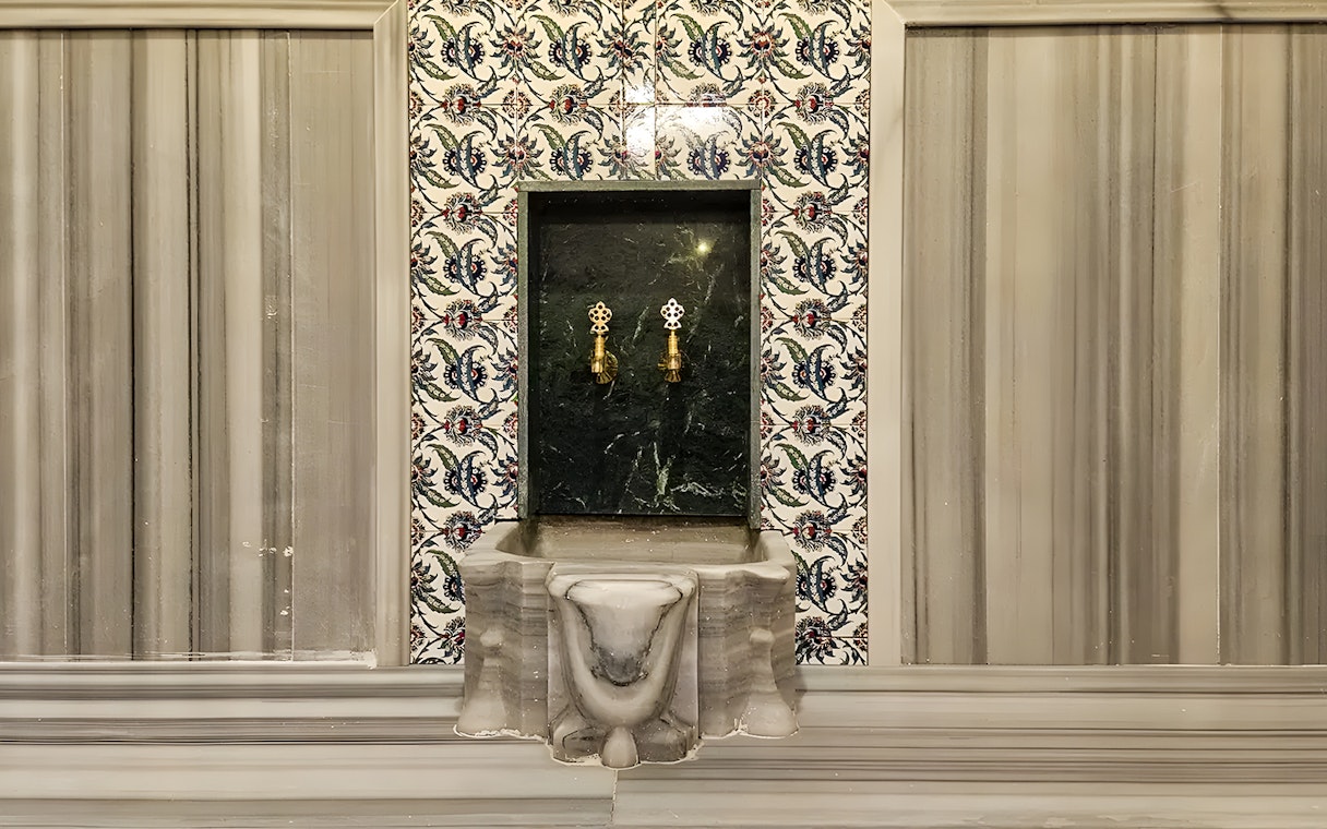 Gedikpasa Historical Hammam marble basin with ornate tile backdrop.