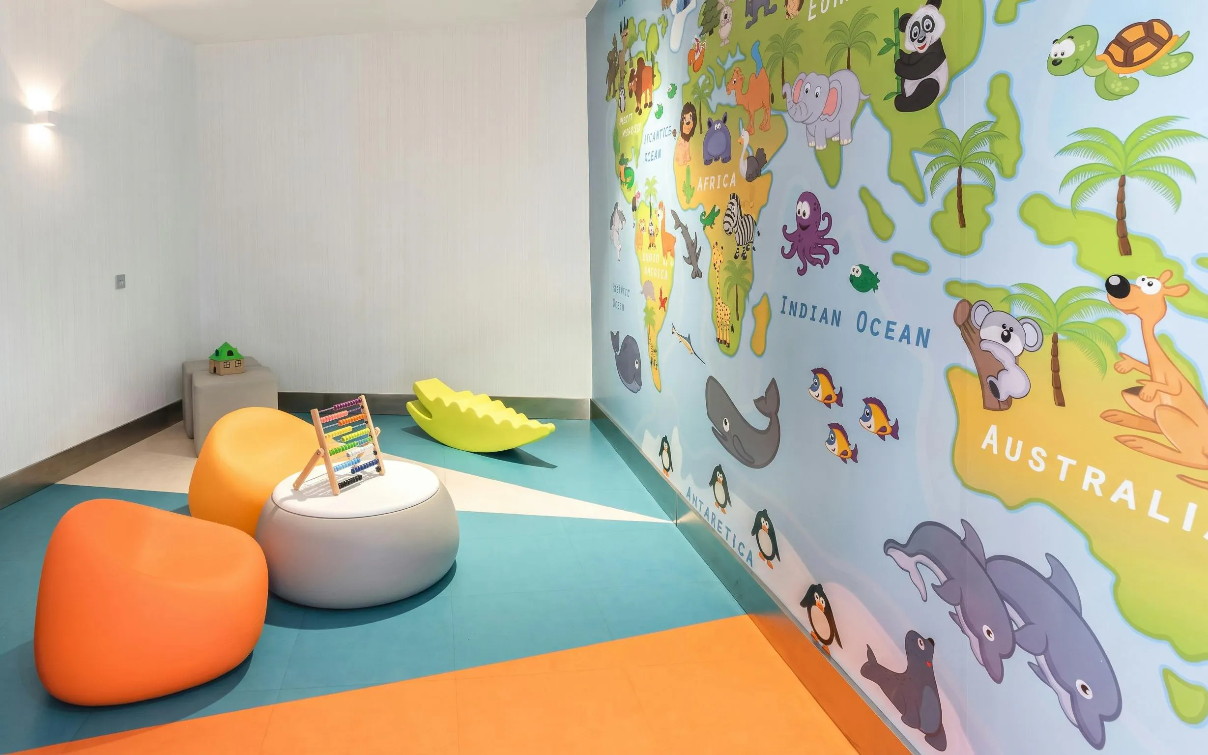 Children's play area with colorful seating and world map mural at Sala VIP Puerta de Alcala, Madrid Airport.