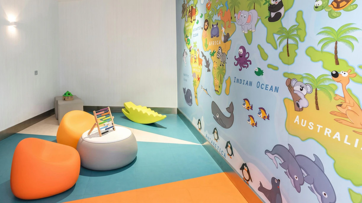 Children's play area with colorful seating and world map mural at Sala VIP Puerta de Alcala, Madrid Airport.