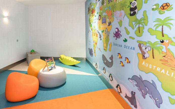 Children's play area with colorful seating and world map mural at Sala VIP Puerta de Alcala, Madrid Airport.
