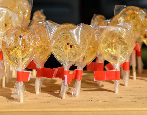 Honey infused lollipop held against the backdrop of a vibrant cityscape in New York City.