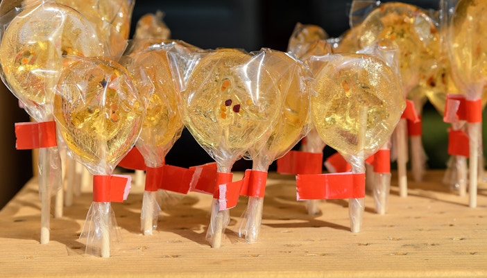Honey infused lollipop held against the backdrop of a vibrant cityscape in New York City.