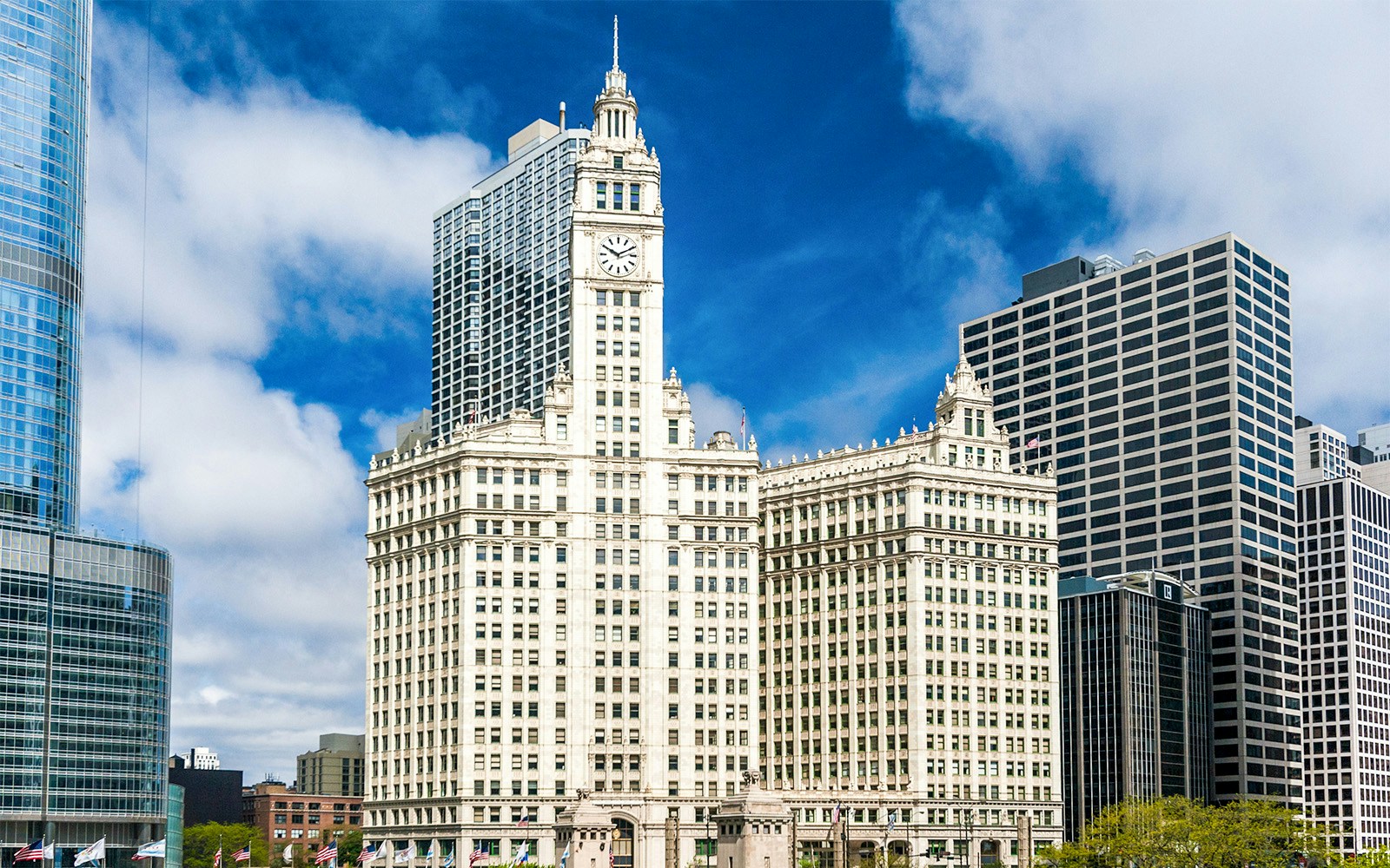 Wrigley Building in Chicago with surrounding skyscrapers under a blue sky.