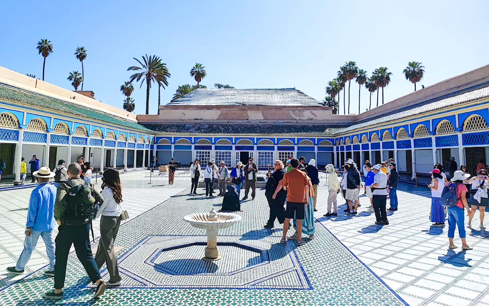 Visitors exploring the courtyard of Bahia Palace in Marrakech, Morocco.
