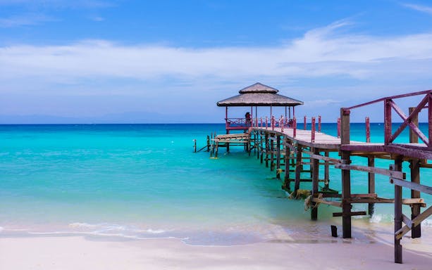 Wooden pier extending into turquoise sea at Kawa Kawa River, Malaysia.