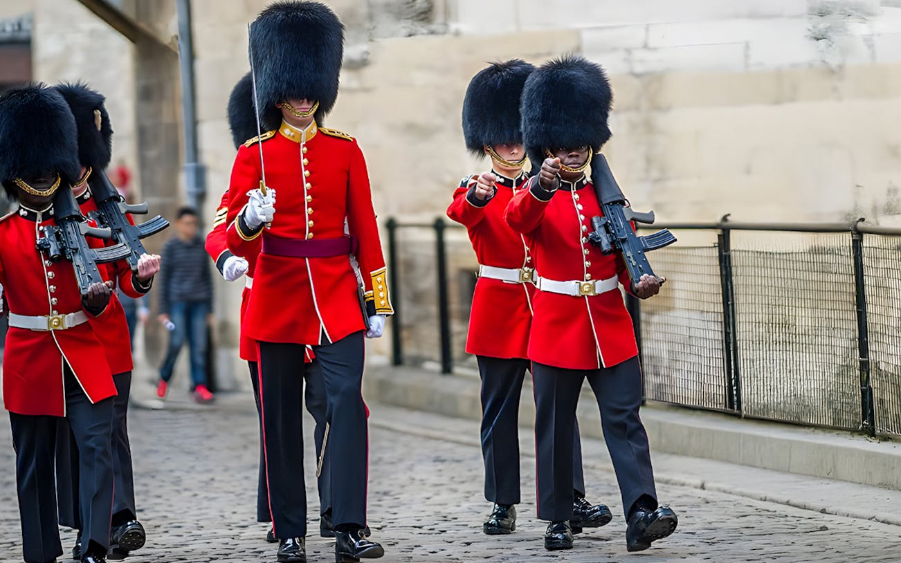 Guards in red uniforms and bearskin hats marching at the Tower of London Opening Ceremony.