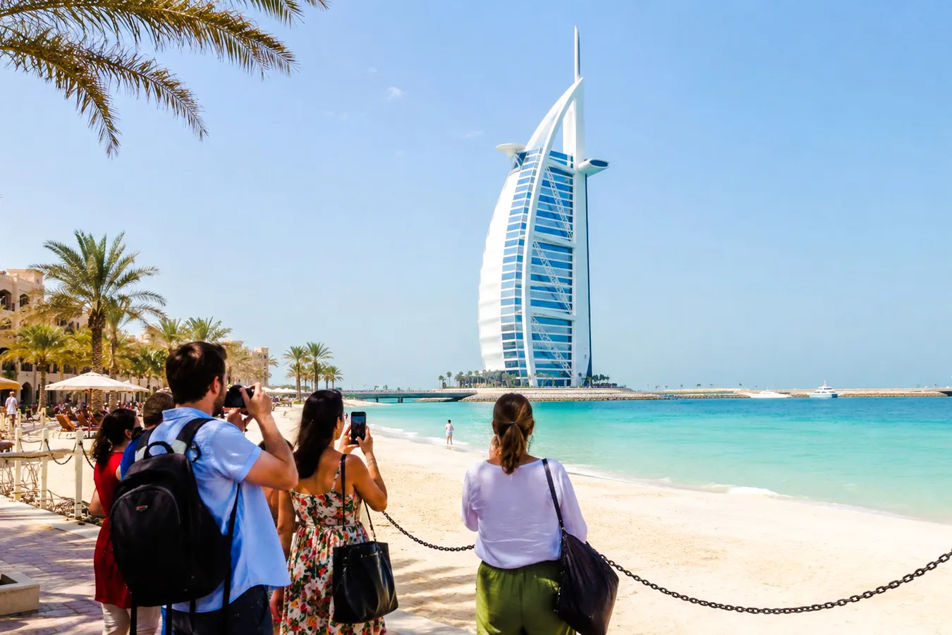 Tourists photographing Burj Al Arab from Jumeirah Beach, Dubai.