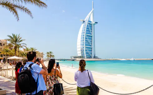 Tourists photographing Burj Al Arab from Jumeirah Beach, Dubai.