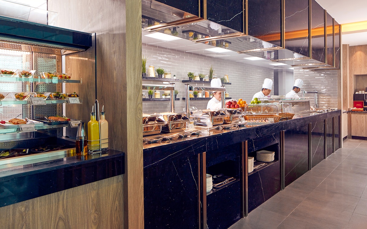 Chefs preparing dishes at a buffet in Dubai International Airport's premium lounge.
