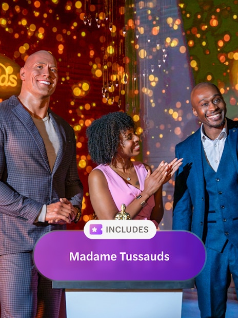 Wax figure of The Rock at Madame Tussauds London with two people celebrating an award.