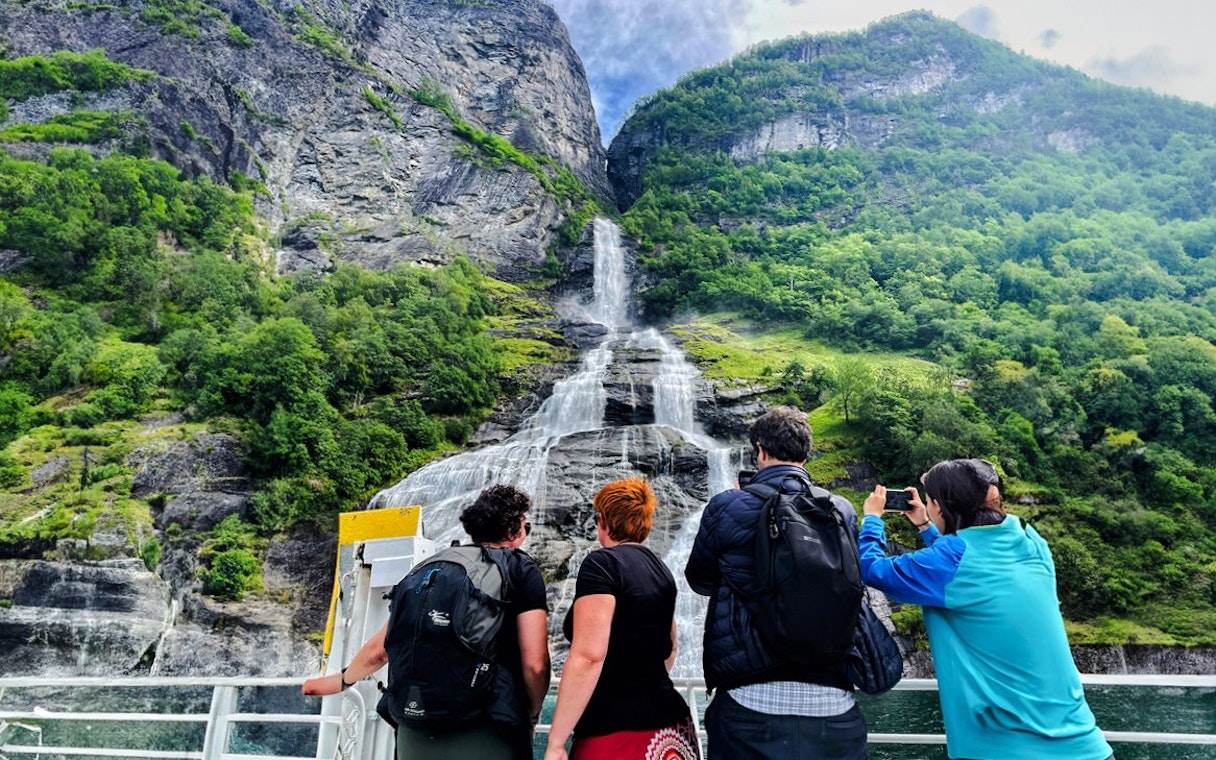 People on a boat viewing the Bachelor Waterfall in Geiranger Fjord, Norway.