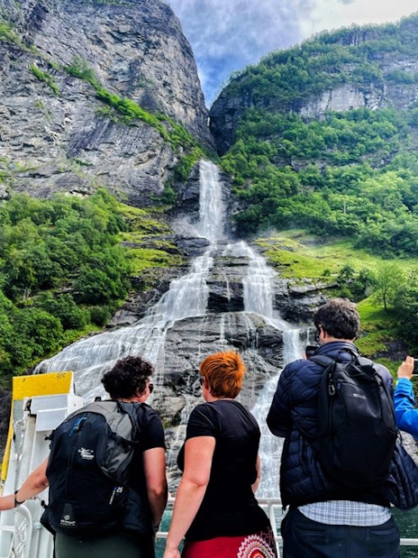 People on a boat viewing the Bachelor Waterfall in Geiranger Fjord, Norway.