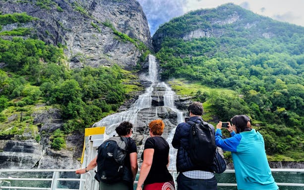People on a boat viewing the Bachelor Waterfall in Geiranger Fjord, Norway.