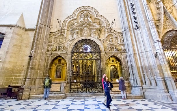 Seville Cathedral interior with ornate stone carvings and visitors exploring.