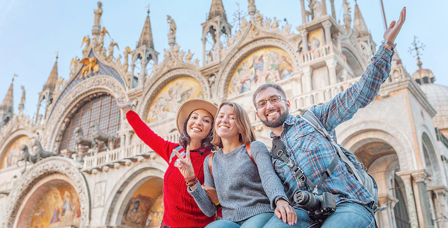 Friends posing in San Marco Square, Venice, with St. Mark's Basilica behind them.
