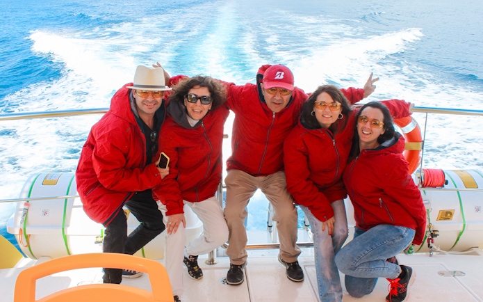 Tourists in red jackets on a boat departing from port for dolphin watching.