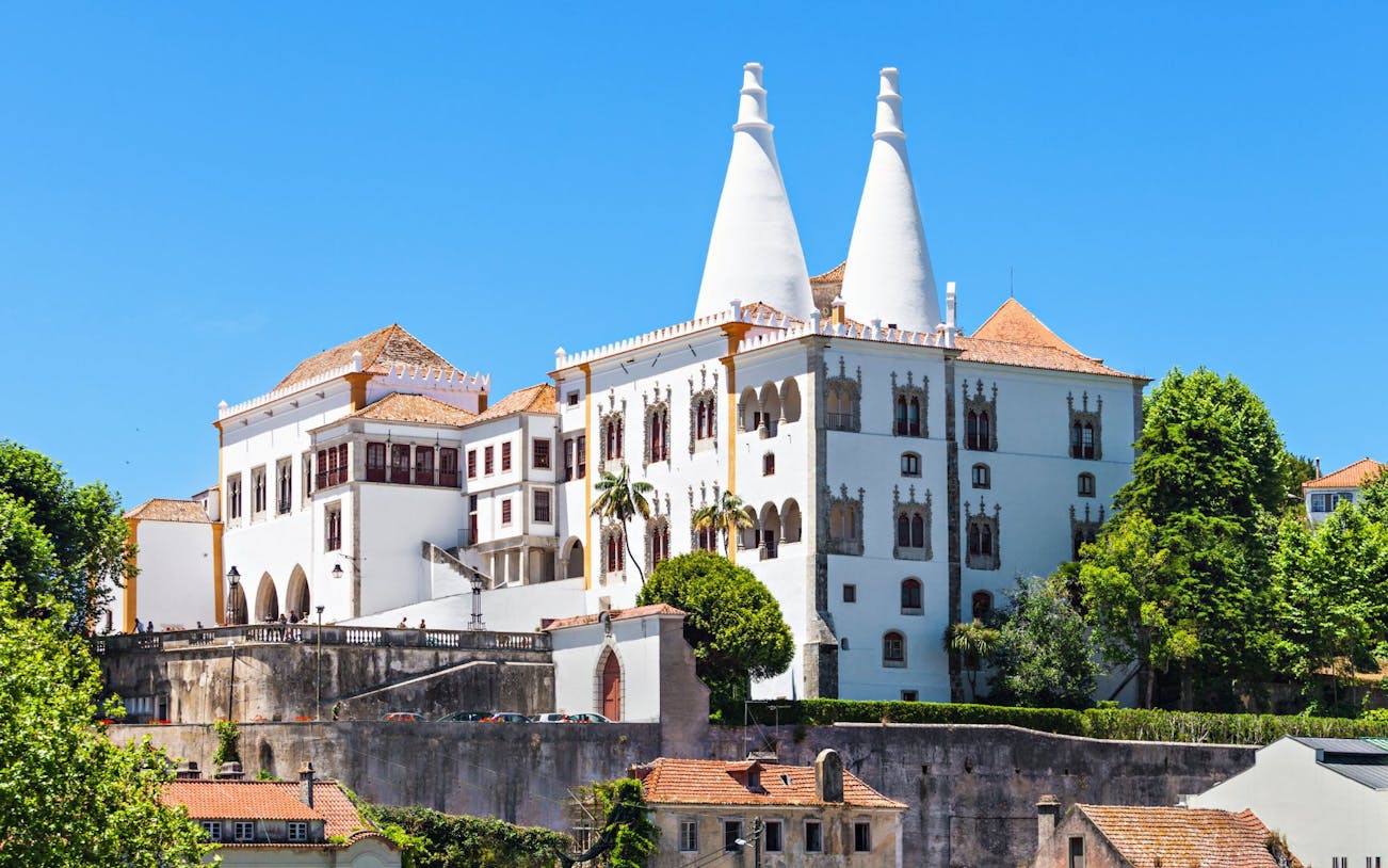 National Palace of Sintra with iconic twin chimneys and lush greenery.