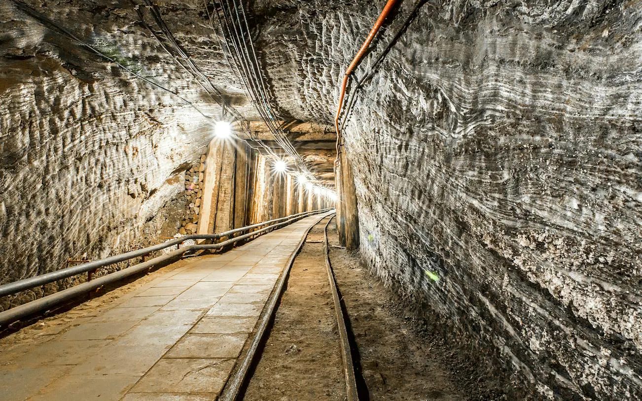Underground passage in Bochnia Salt Mine, Krakow, with illuminated walls and tracks.